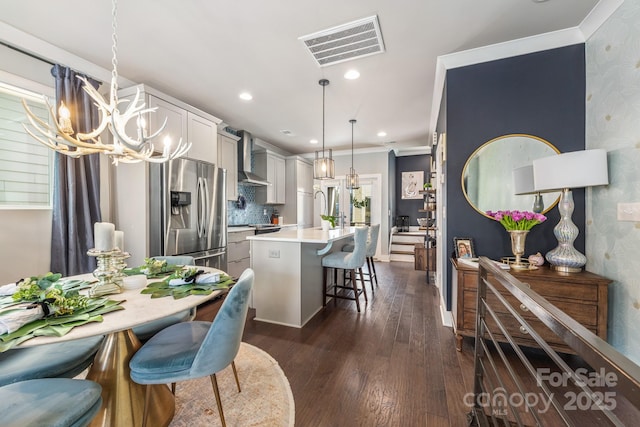 kitchen featuring visible vents, stainless steel fridge with ice dispenser, dark wood finished floors, a kitchen bar, and an inviting chandelier