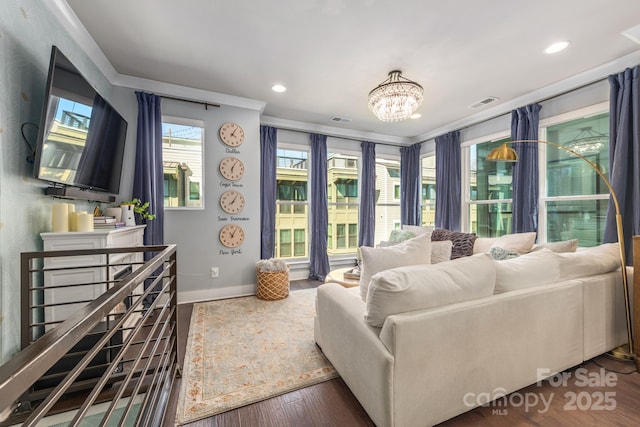 living room with a chandelier, visible vents, ornamental molding, and wood finished floors