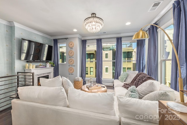 living area with visible vents, wood finished floors, recessed lighting, an inviting chandelier, and crown molding