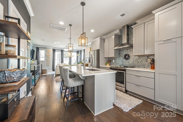 kitchen with visible vents, open floor plan, light countertops, stainless steel appliances, and wall chimney exhaust hood