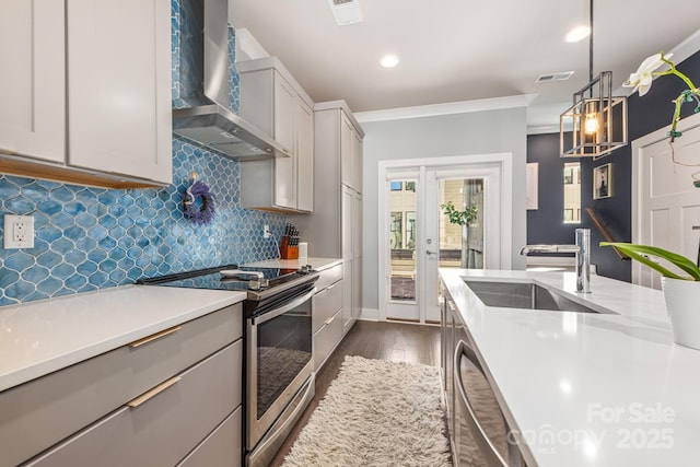 kitchen featuring visible vents, a sink, light countertops, appliances with stainless steel finishes, and wall chimney range hood