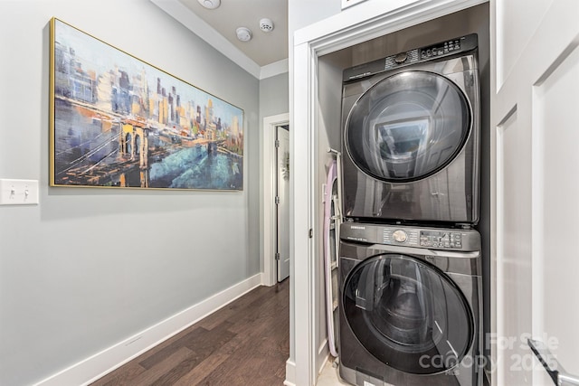 laundry area with stacked washer / drying machine, baseboards, dark wood finished floors, and laundry area