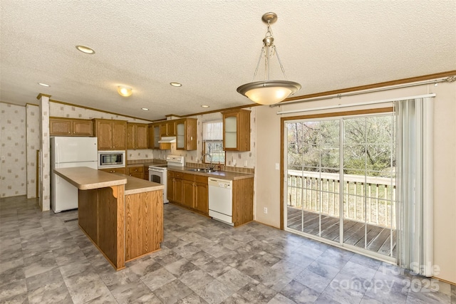 kitchen with lofted ceiling, white appliances, a center island, under cabinet range hood, and a sink