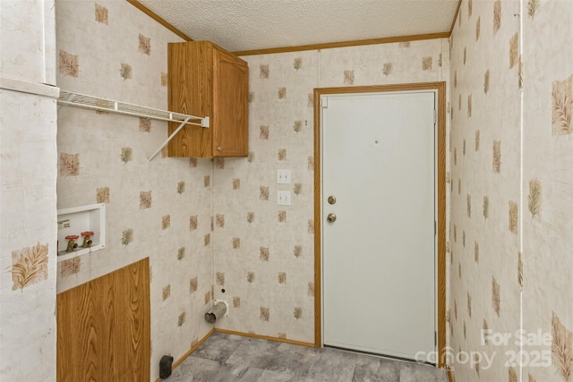 clothes washing area with crown molding, washer hookup, a textured ceiling, wallpapered walls, and cabinet space