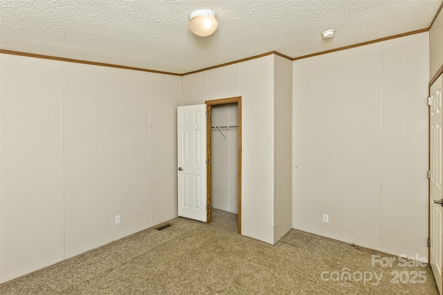 unfurnished bedroom with visible vents, ornamental molding, carpet, and a textured ceiling