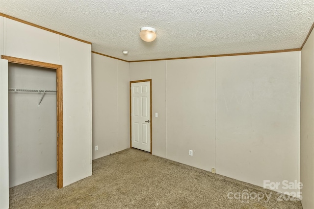 unfurnished bedroom featuring a textured ceiling, carpet floors, ornamental molding, and a closet