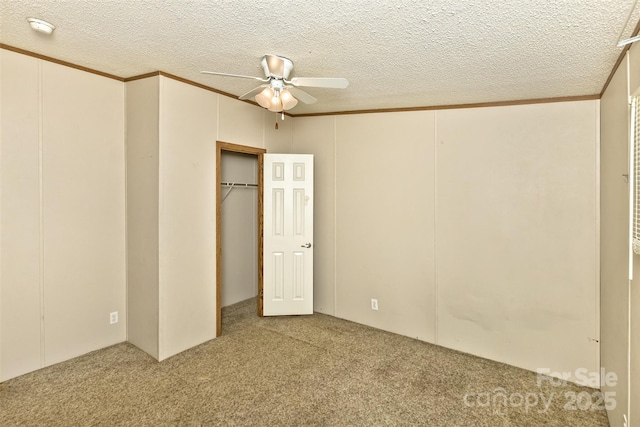 unfurnished bedroom featuring carpet, a closet, a ceiling fan, a textured ceiling, and ornamental molding