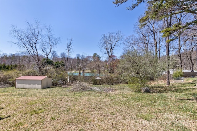view of yard featuring an outbuilding, a view of trees, a pole building, and a water view