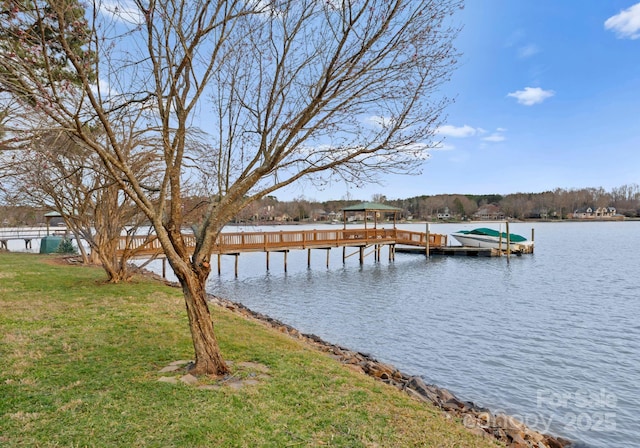 view of dock with a yard and a water view