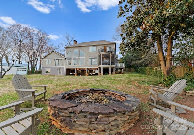 rear view of property featuring a yard, fence, a chimney, and an outdoor fire pit