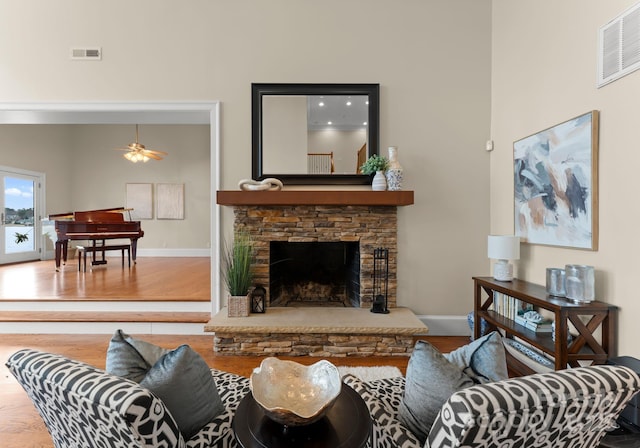 living area featuring visible vents, baseboards, a ceiling fan, and wood finished floors