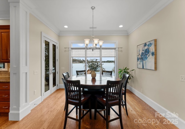 dining space featuring a notable chandelier, light wood-style flooring, and ornamental molding