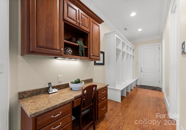 home office featuring wood finished floors, visible vents, recessed lighting, built in desk, and crown molding