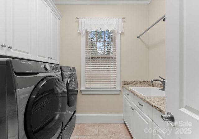 washroom with cabinet space, light tile patterned floors, washer and dryer, and a sink