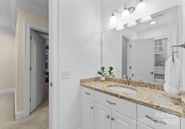 bathroom featuring visible vents, vanity, crown molding, and baseboards