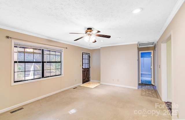 empty room featuring visible vents, light colored carpet, a textured ceiling, and ornamental molding