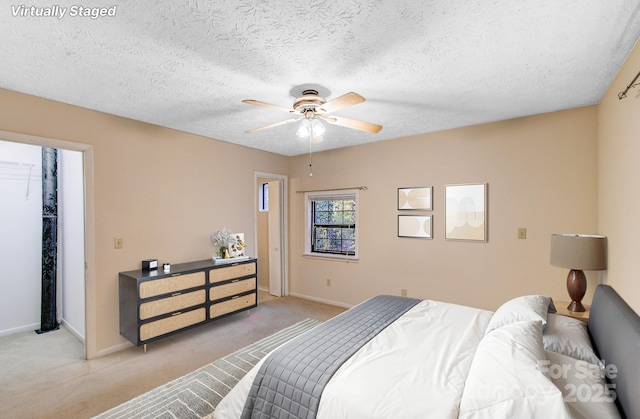 bedroom with a spacious closet, baseboards, and light carpet