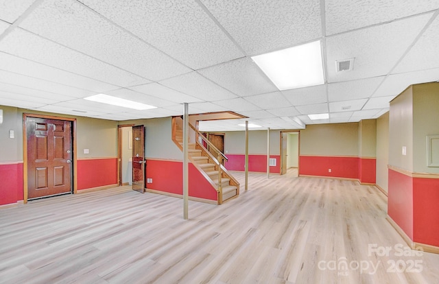 finished basement featuring stairs, wood finished floors, visible vents, and a drop ceiling