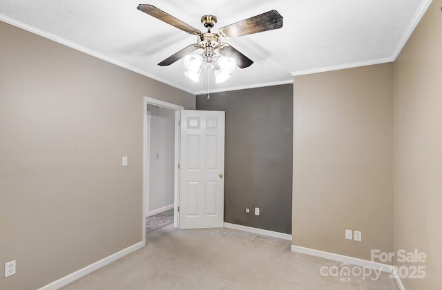 spare room featuring baseboards, light colored carpet, ceiling fan, and crown molding