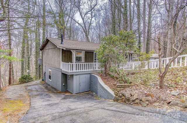 view of front of property with aphalt driveway, covered porch, and roof with shingles