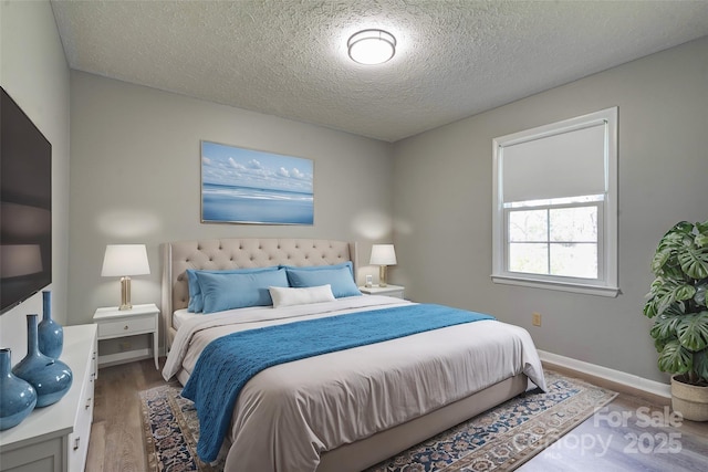 bedroom featuring wood finished floors, baseboards, and a textured ceiling