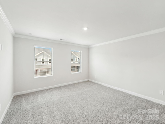 carpeted spare room featuring visible vents, baseboards, and ornamental molding