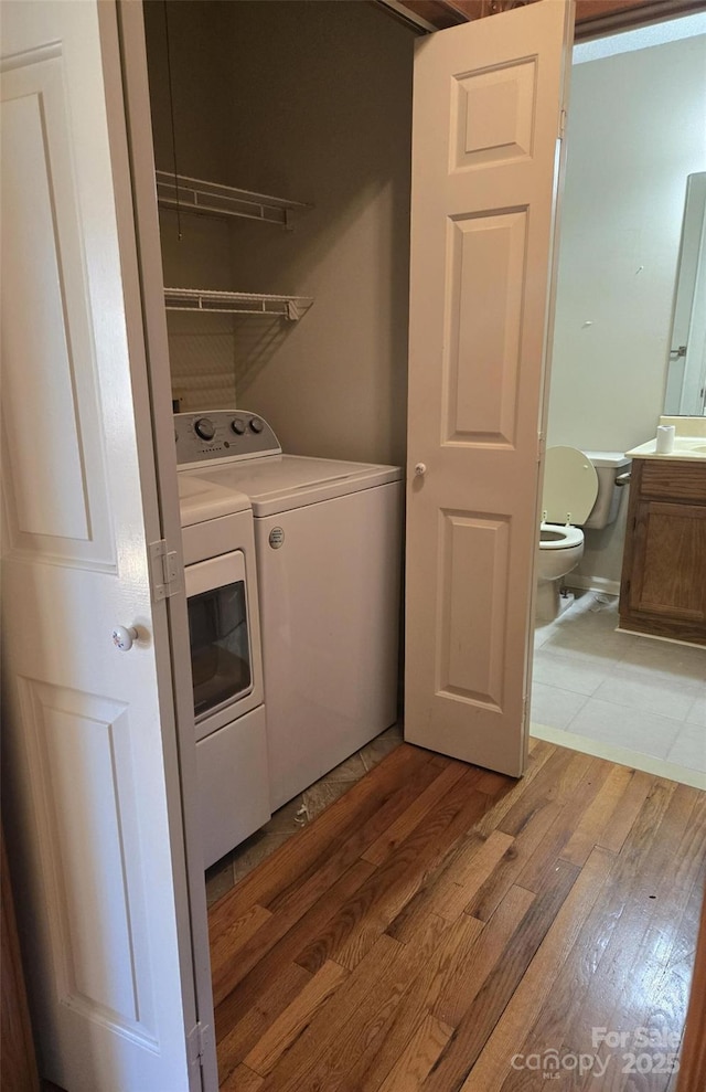 laundry room with laundry area, light wood finished floors, and washer and clothes dryer