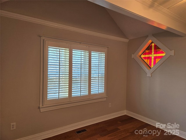 empty room with visible vents, dark wood finished floors, crown molding, baseboards, and vaulted ceiling