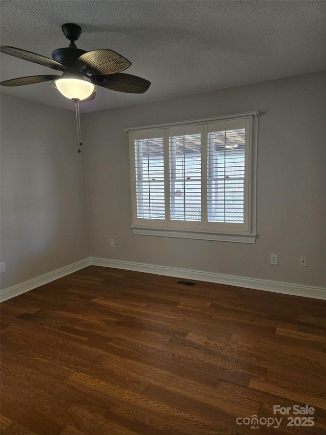 spare room with visible vents, baseboards, a textured ceiling, and dark wood-style floors