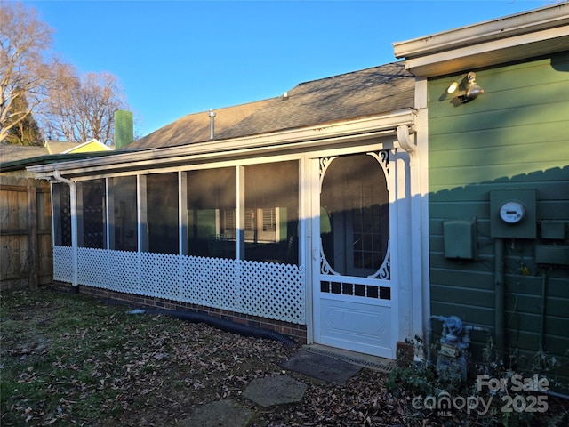 back of property featuring fence, a sunroom, and roof with shingles