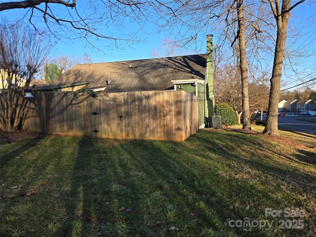 view of side of home featuring central AC unit, a lawn, and a chimney