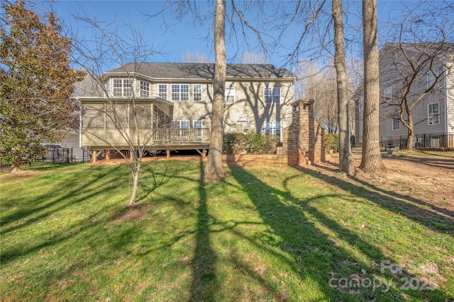 rear view of property featuring a deck, a yard, fence, and a sunroom