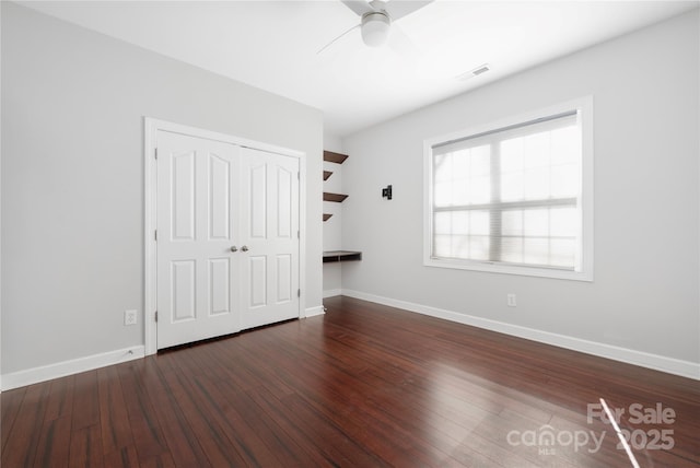 unfurnished bedroom with visible vents, baseboards, dark wood-style flooring, ceiling fan, and a closet