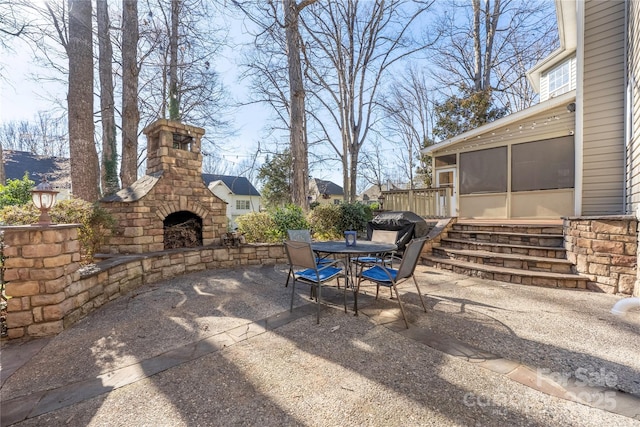 view of patio / terrace with outdoor dining area, an outdoor stone fireplace, and a sunroom