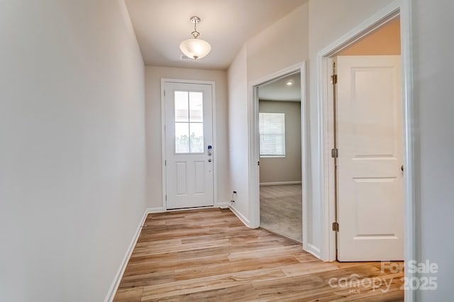 doorway to outside featuring light wood-style flooring and baseboards