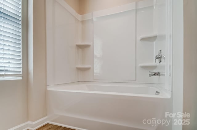 bathroom featuring washtub / shower combination and baseboards