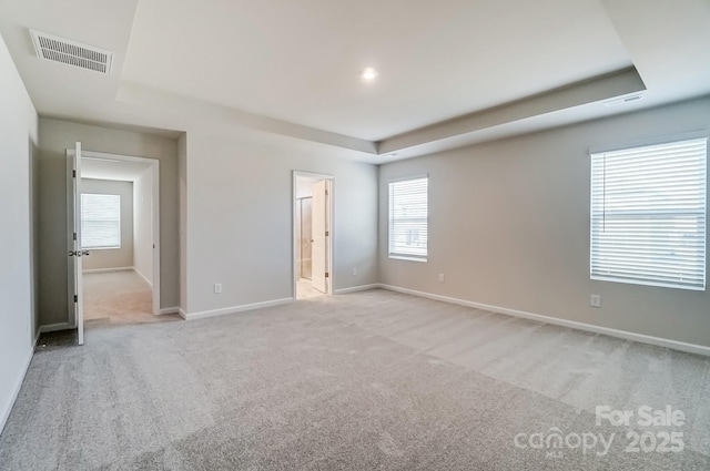 unfurnished bedroom with light colored carpet, visible vents, ensuite bathroom, and baseboards