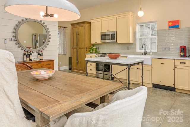 kitchen with pendant lighting, a sink, tasteful backsplash, appliances with stainless steel finishes, and light countertops