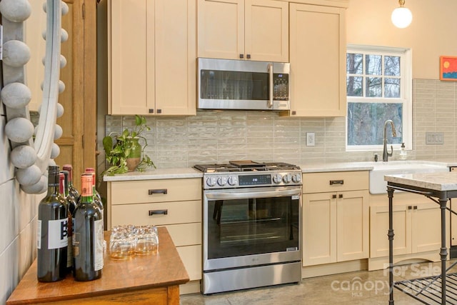 kitchen featuring light tile patterned floors, a sink, stainless steel appliances, pendant lighting, and backsplash