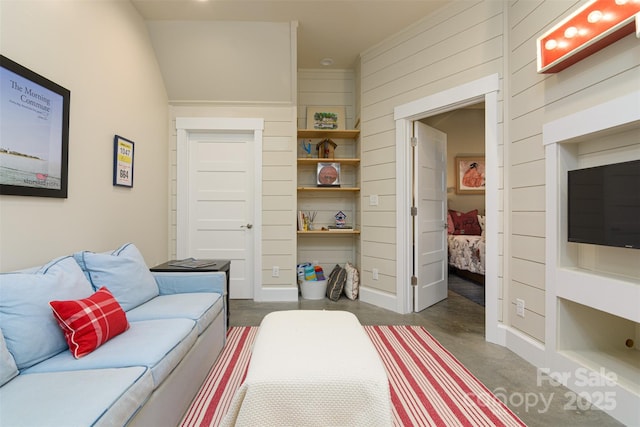 bedroom with finished concrete flooring and wood walls