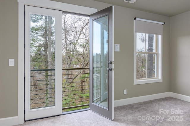 doorway with plenty of natural light, visible vents, baseboards, and carpet floors