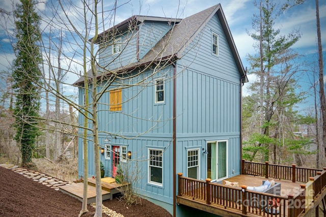 rear view of house with roof with shingles, board and batten siding, and a deck