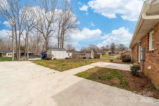 view of yard featuring a residential view, driveway, and an outdoor structure