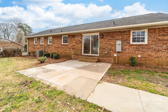 rear view of property featuring a patio, cooling unit, entry steps, a lawn, and brick siding