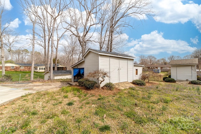 exterior space with an outbuilding, concrete driveway, and fence