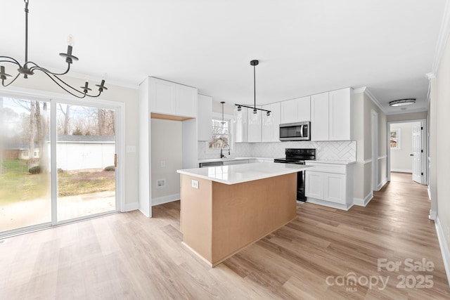 kitchen with stainless steel microwave, black electric range oven, white cabinetry, and an inviting chandelier