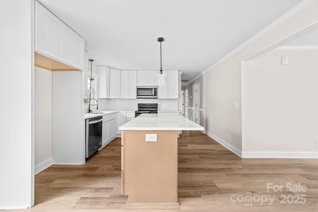 kitchen featuring ornamental molding, backsplash, white cabinetry, light wood-style floors, and appliances with stainless steel finishes