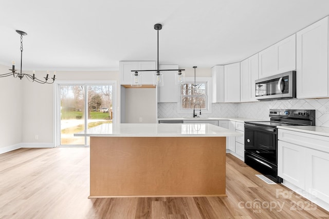 kitchen with black electric range oven, a sink, stainless steel microwave, backsplash, and a center island