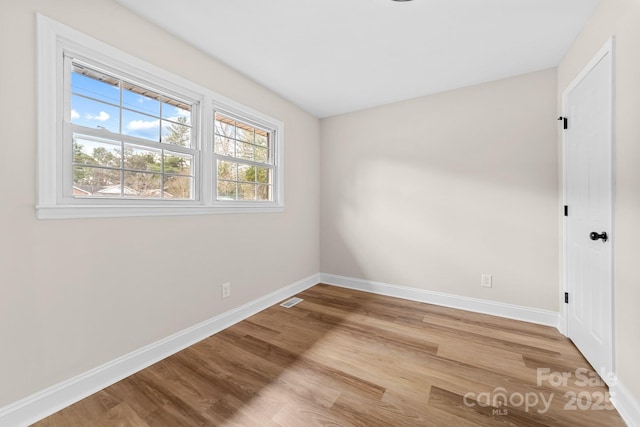 empty room with visible vents, baseboards, and wood finished floors