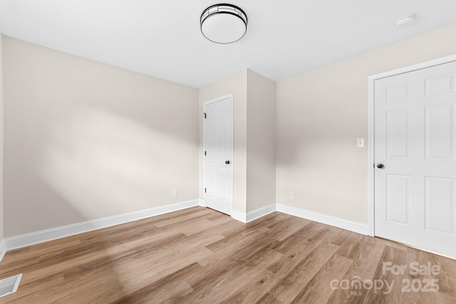 unfurnished bedroom with visible vents, wood finished floors, and baseboards